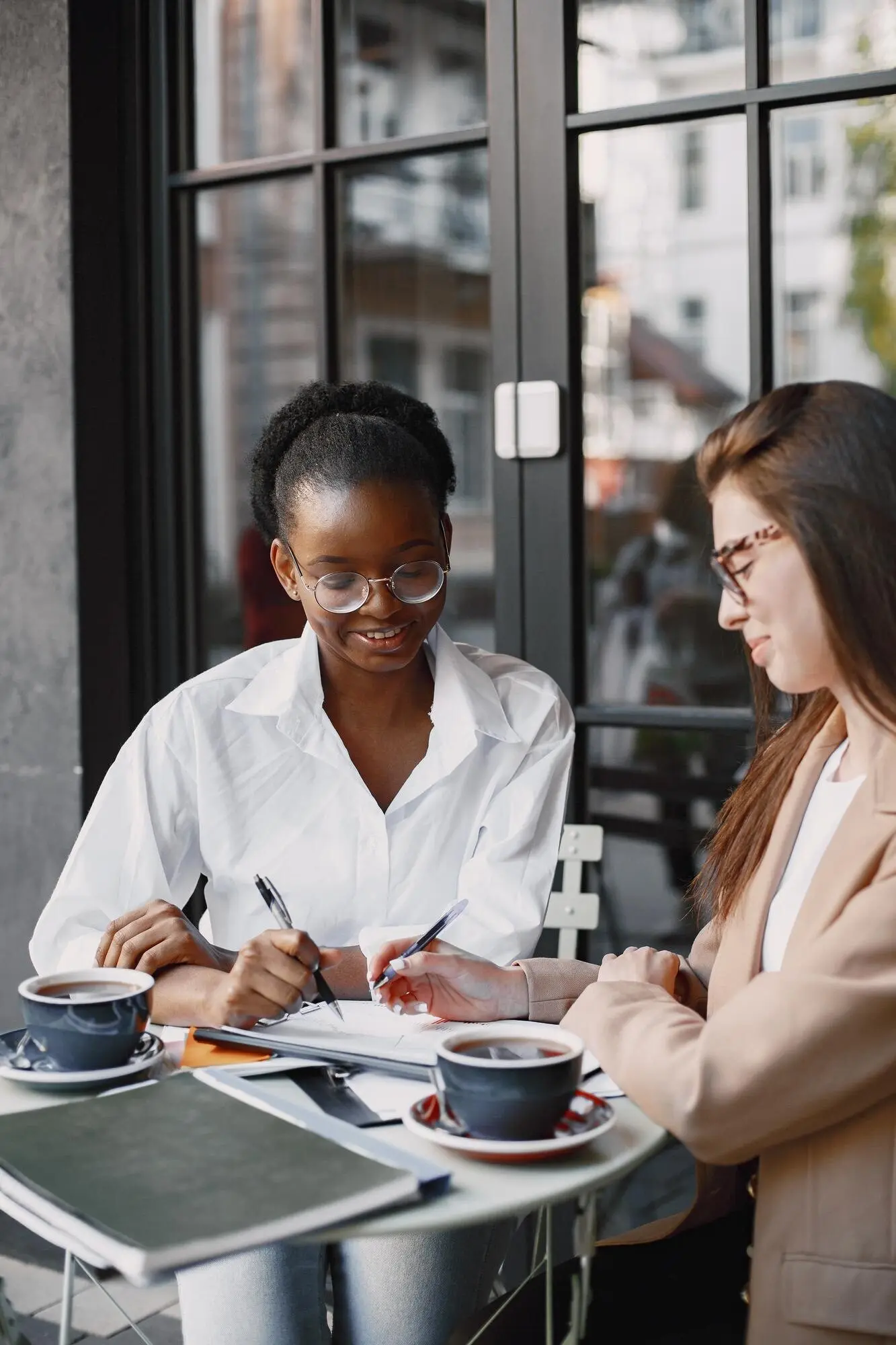 Female colleagues discussing data at an outdoor cafe.