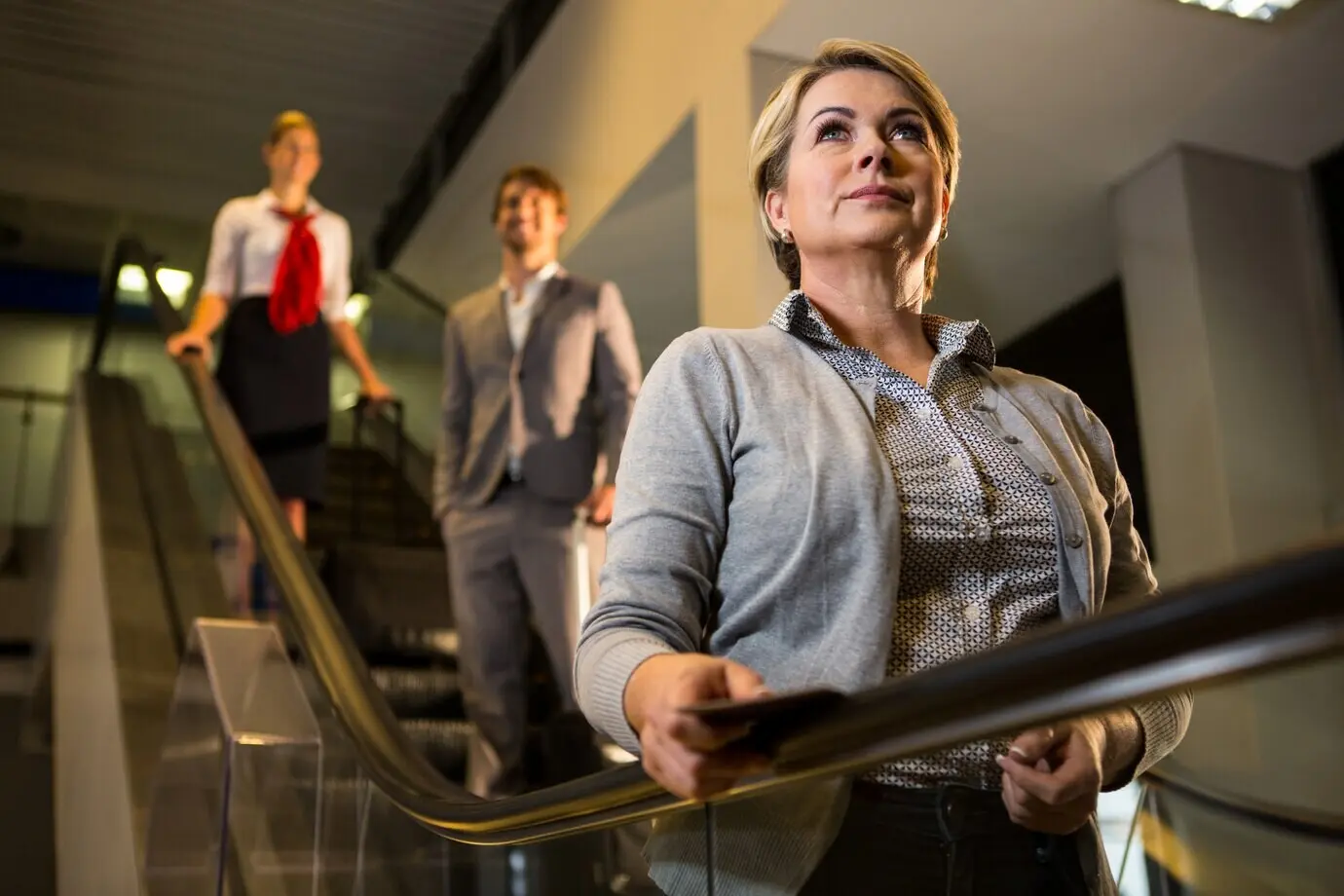 A businesswoman on an escalator with a boarding pass.