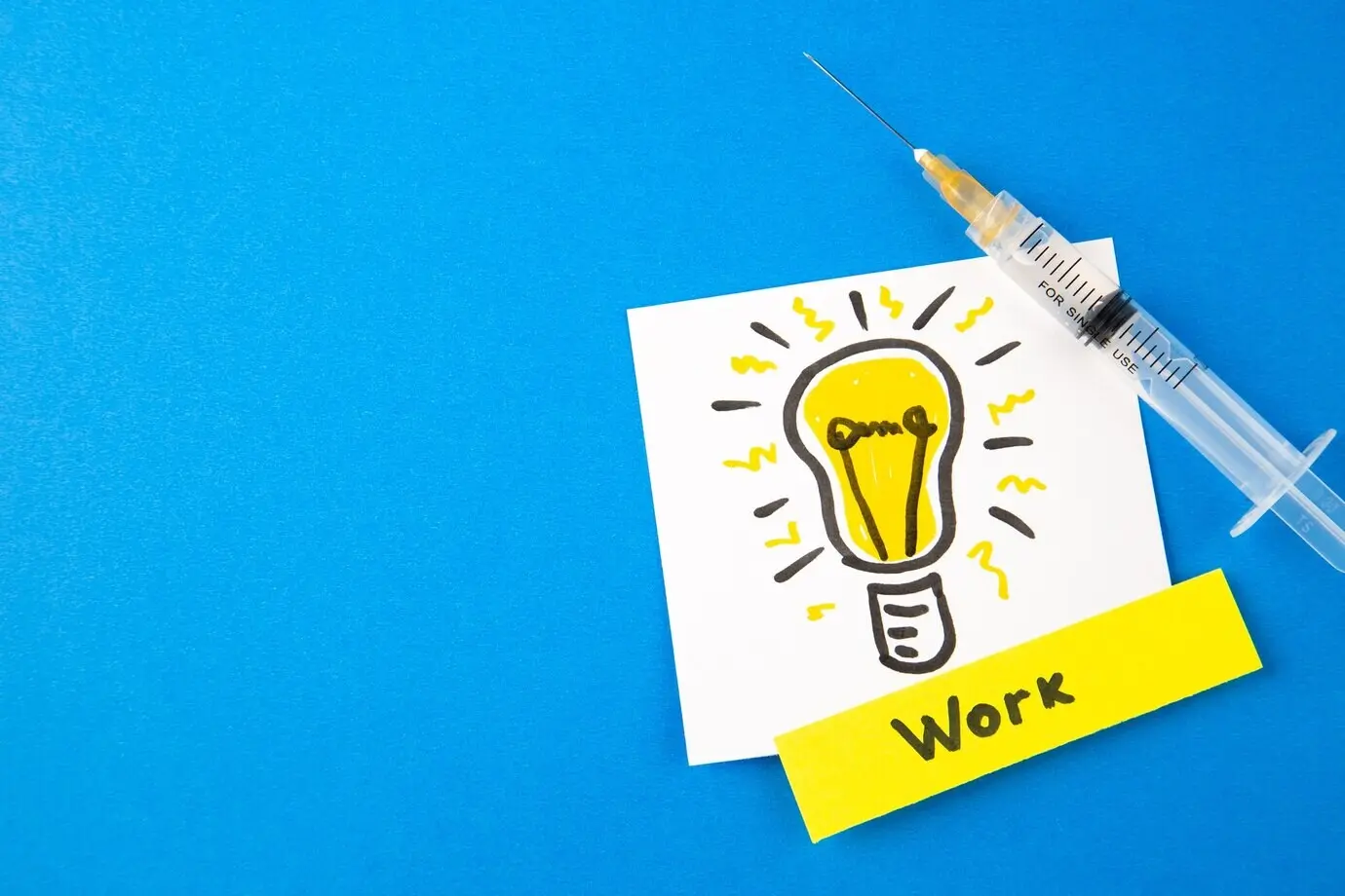 Top view of an antivirus injection with a lightbulb illustration on a blue background; hospital, virus, pandemic, lab, COVID, cure, health, drug, medicine.